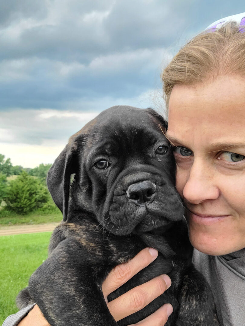 A woman holding a black dog in her arms.